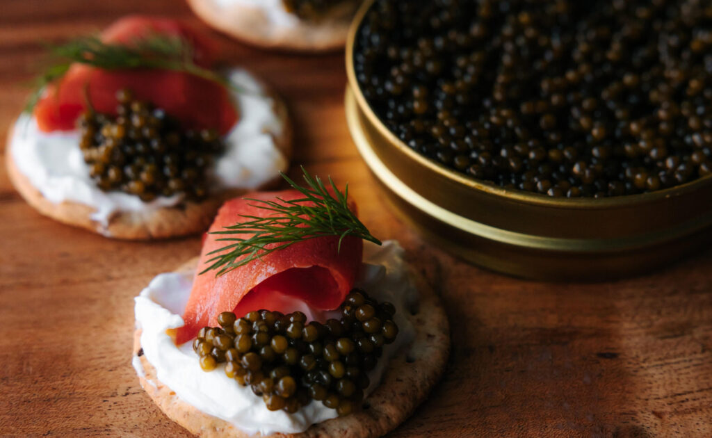 Caviar on crackers with salmon and cream and a caviar tin with 